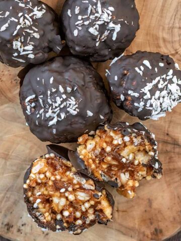 Five crispy date caramel balls with one cut open.
