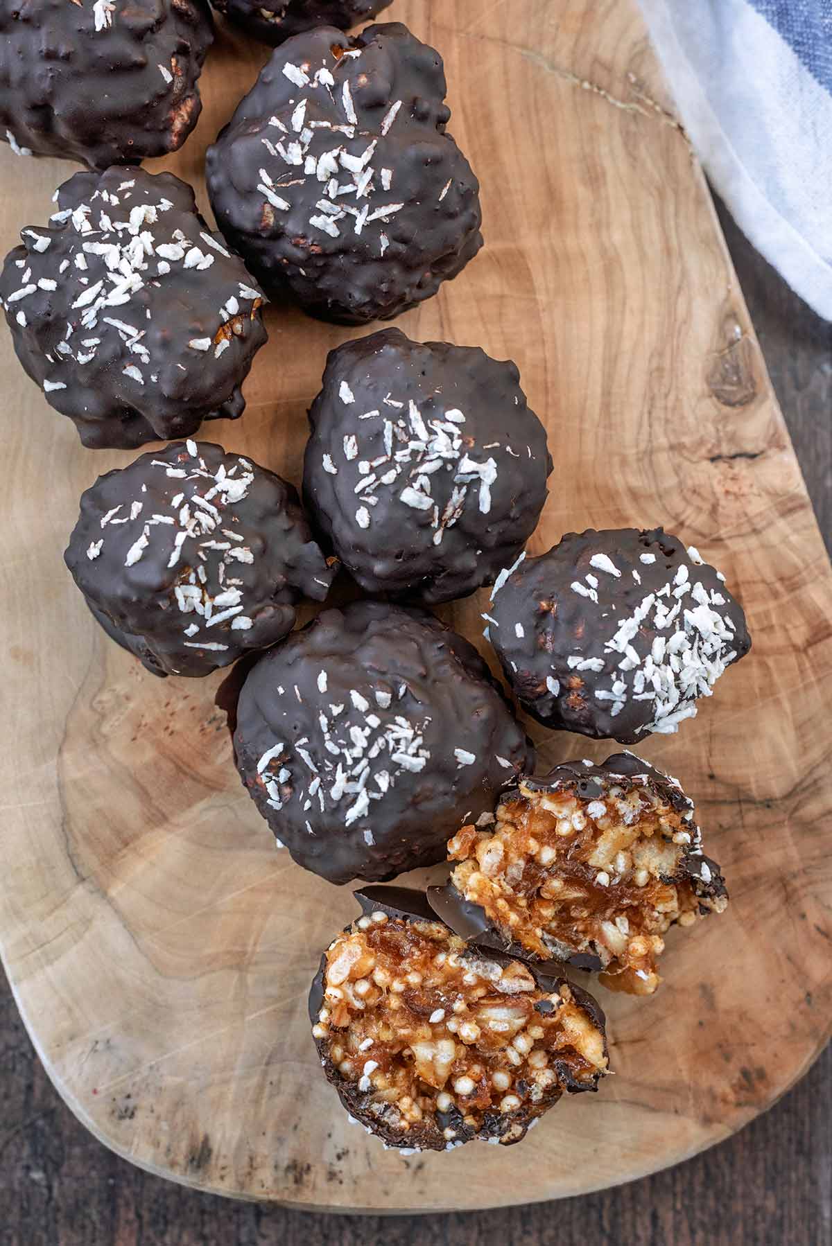 Chocolate covered crispy caramel balls on a serving board.